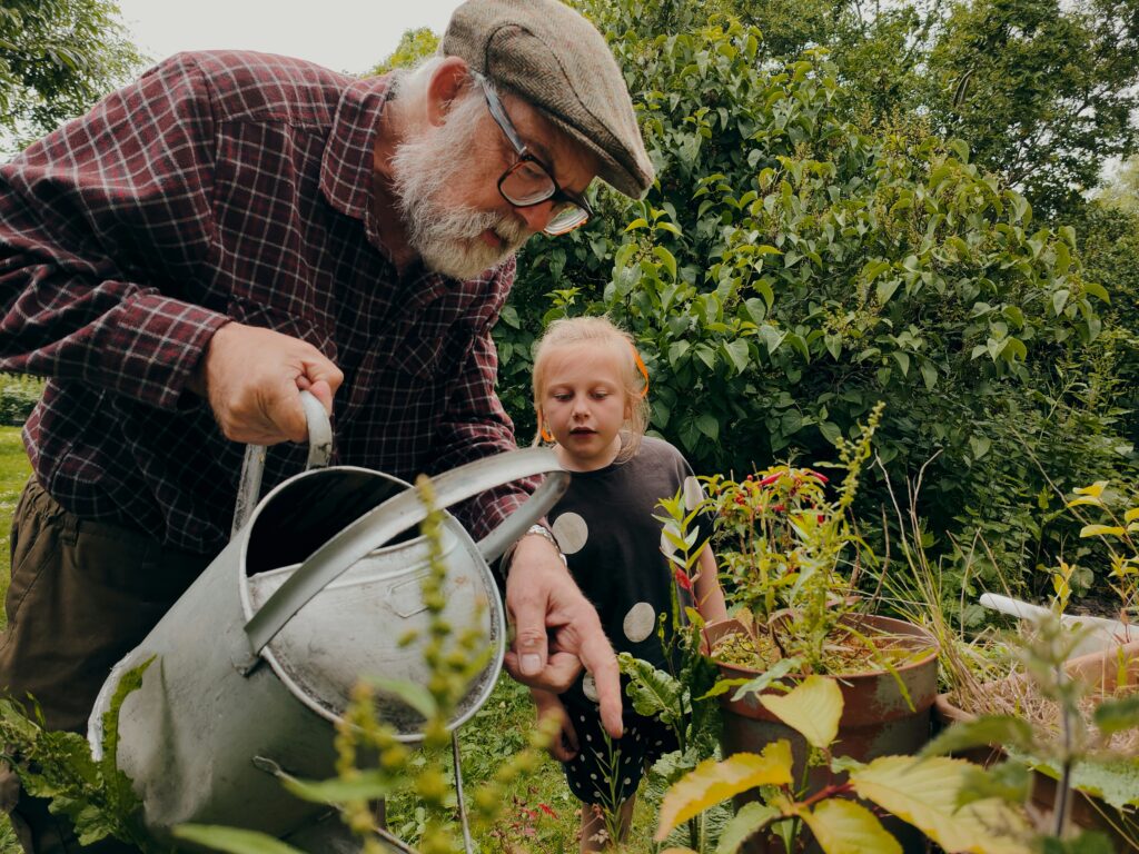Gardner watering plants with a child
